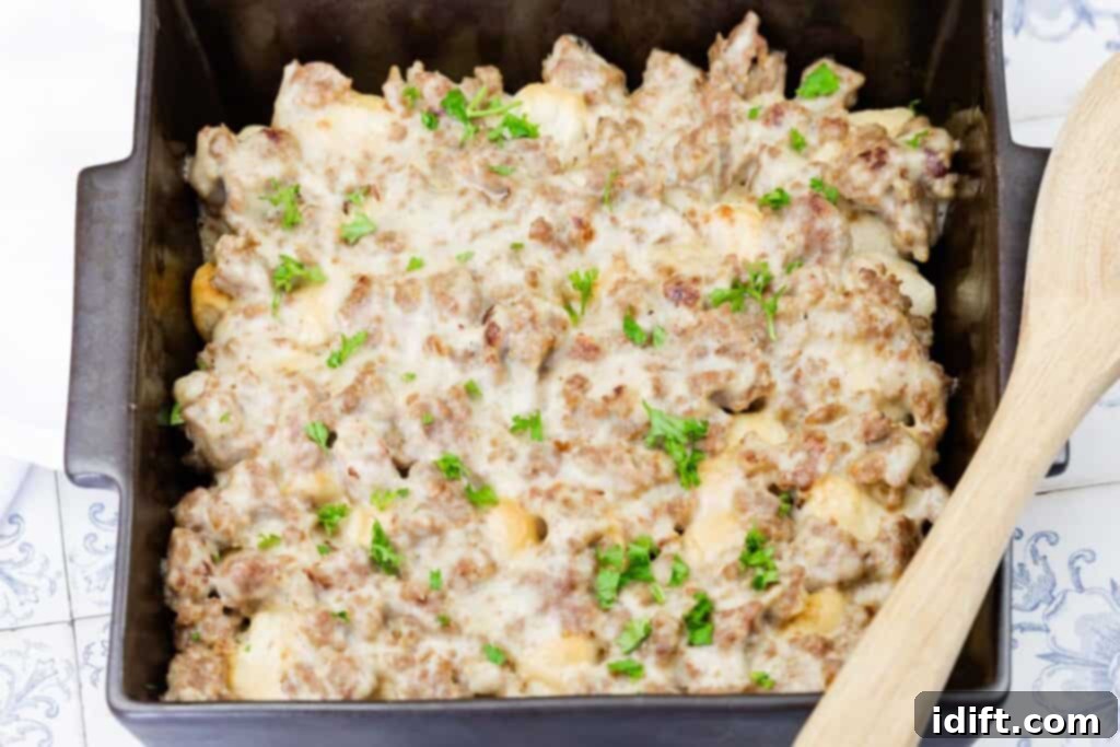A casserole dish filled with a baked mixture of ground meat, cheese, and chopped parsley, with a wooden spoon on the side.