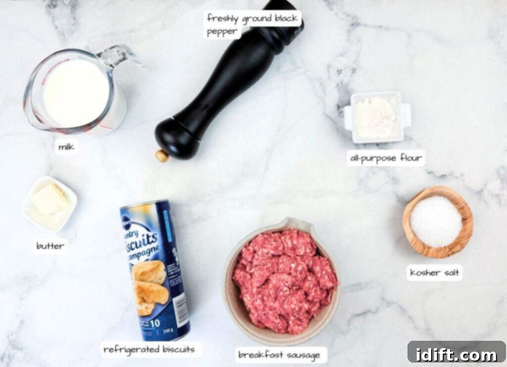 Ingredients for biscuits and gravy laid out on a counter: milk, butter, refrigerated biscuits, breakfast sausage, flour, black pepper, and kosher salt.