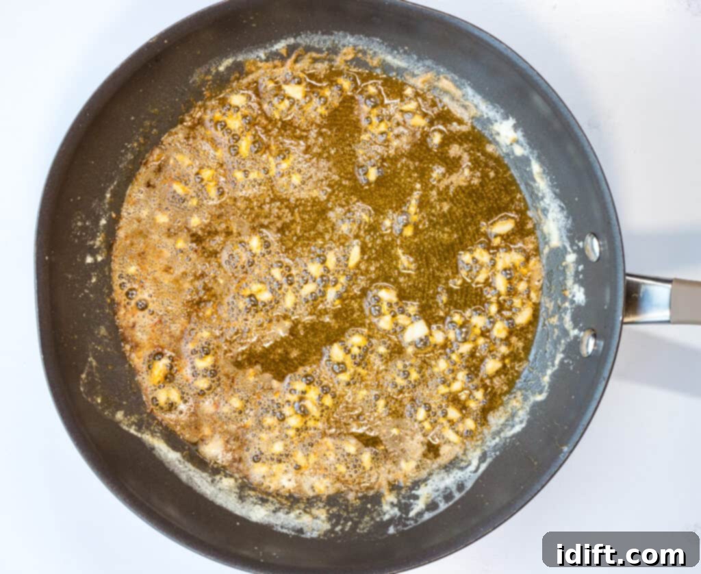 Zesty Garlic Butter Shrimp 7 The vibrant addition of fresh lemon juice and zest into the simmering butter sauce in a skillet, creating the zesty scampi base.