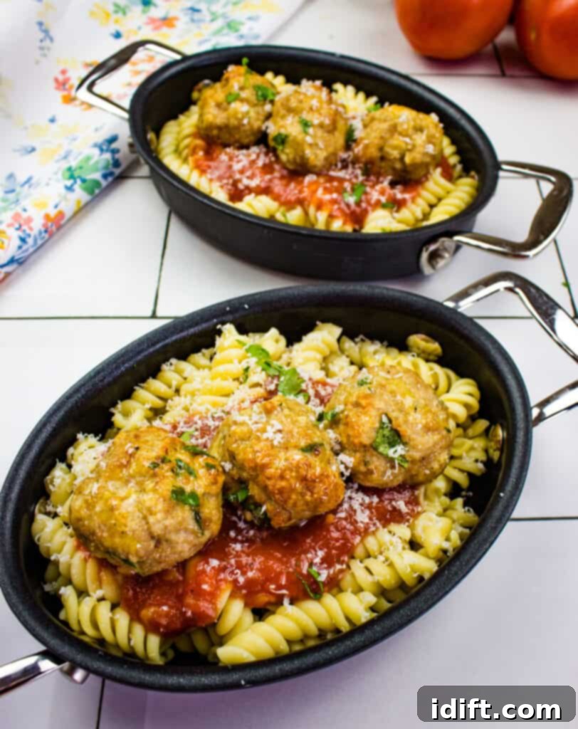 Air fryer turkey meatballs served over noodles with a rich sauce, garnished with fresh herbs.