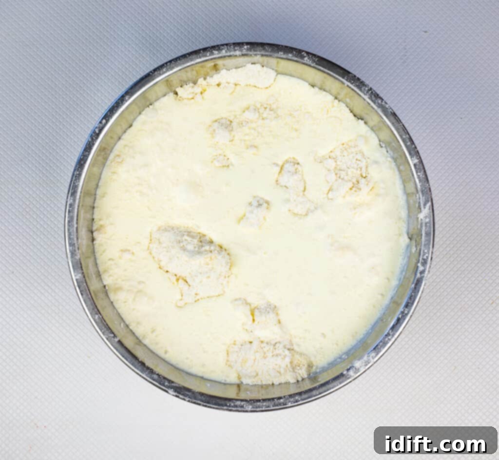 Pouring cream into the flour and butter mixture, preparing to form the biscuit dough.