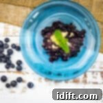 A blue bowl filled with blueberries and mint, creating a delightful blueberry grunt.