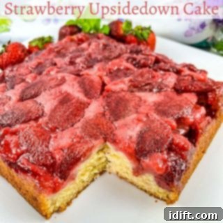 A vibrant Strawberry Upside Down Cake with a slice removed, revealing the juicy strawberries at the top and the moist cake underneath.
