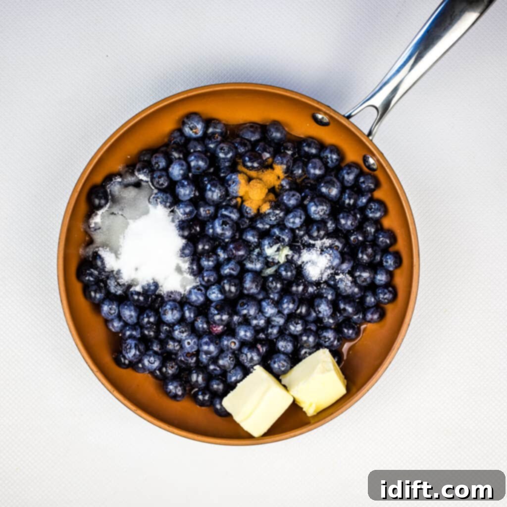 Blueberries, water, sugar, lemon, and butter simmering together in a skillet, forming the base of the grunt.