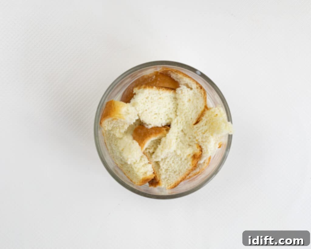 Slices of white bread soaking in milk in a bowl.