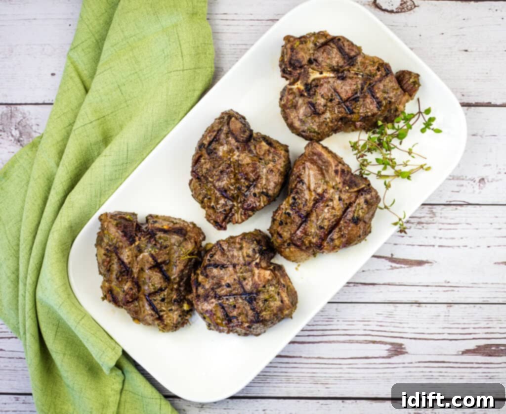 Two exquisitely smoked lamb chops, perfectly seared and garnished, resting on a plate.