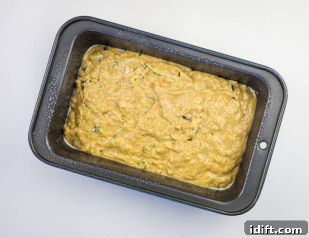 Pouring zucchini bread batter into a loaf pan, ready for baking