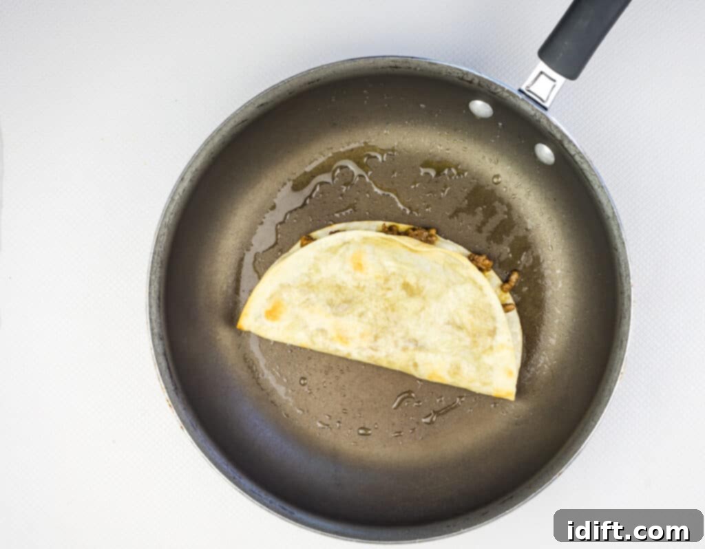 Folded tortilla with filling shallow frying in oil