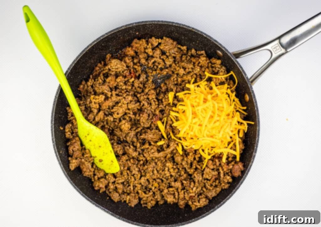 Shredded cheese being mixed into the hot meat filling
