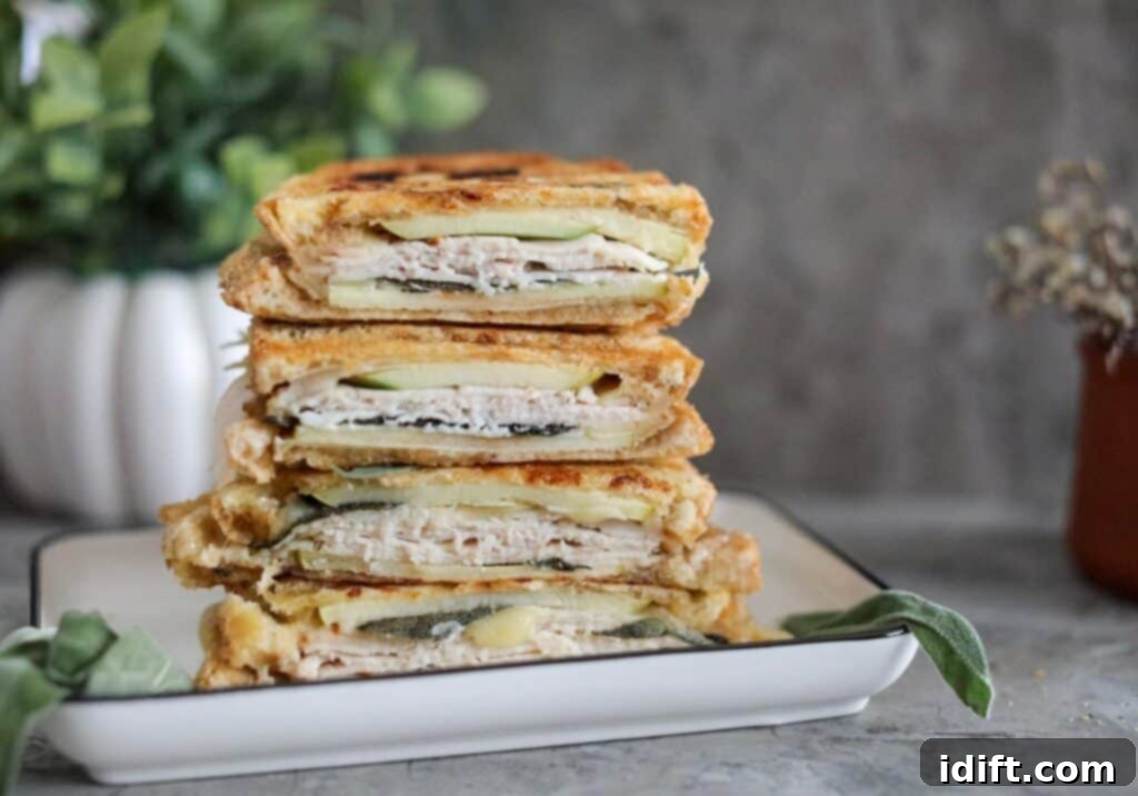 A freshly pressed Turkey & apple panini cut in half, revealing the melted cheese and layered ingredients.