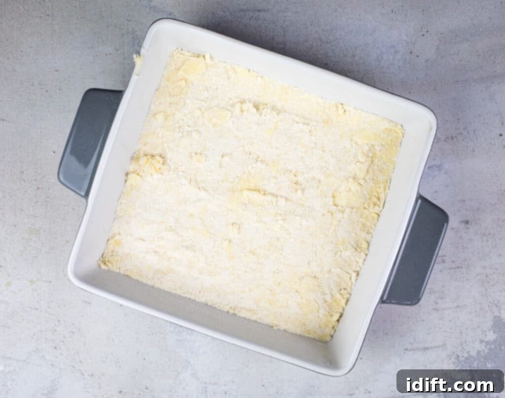 Tangy Cranberry Squares 10 The shortbread dough firmly pressed into the bottom of a baking dish, prepared for its initial bake.