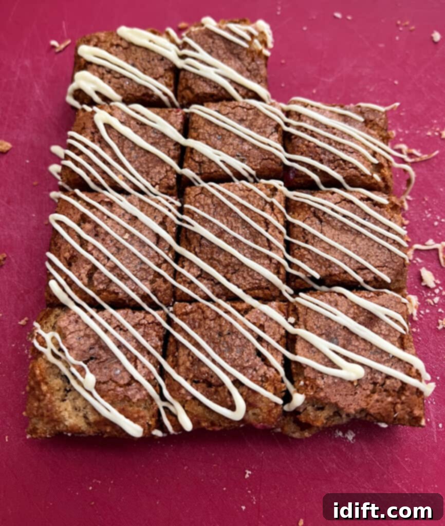 Tangy Cranberry Squares 7 The finished cranberry bars elegantly drizzled with melted white chocolate, adding a beautiful contrast and creamy touch.