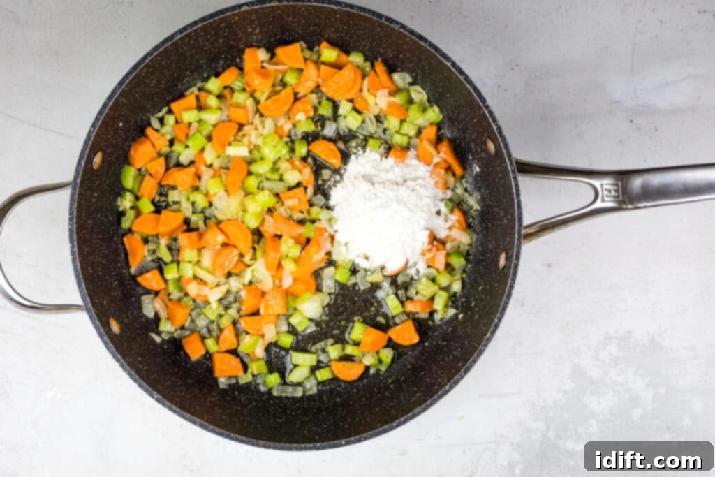 Flour being sprinkled over the sautéed vegetables in a pot.