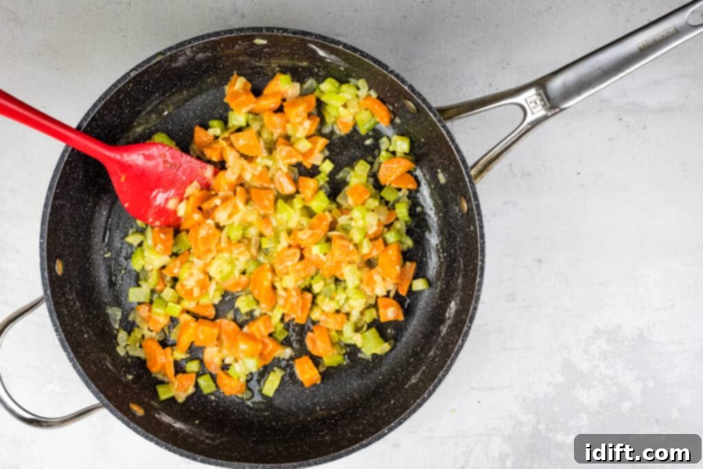 The flour and vegetables being mixed thoroughly to form a roux.