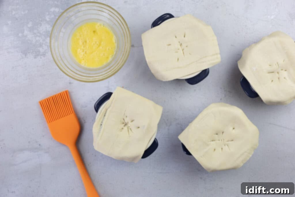 Individual pot pies topped with puff pastry, scored with slits, and brushed with egg wash.