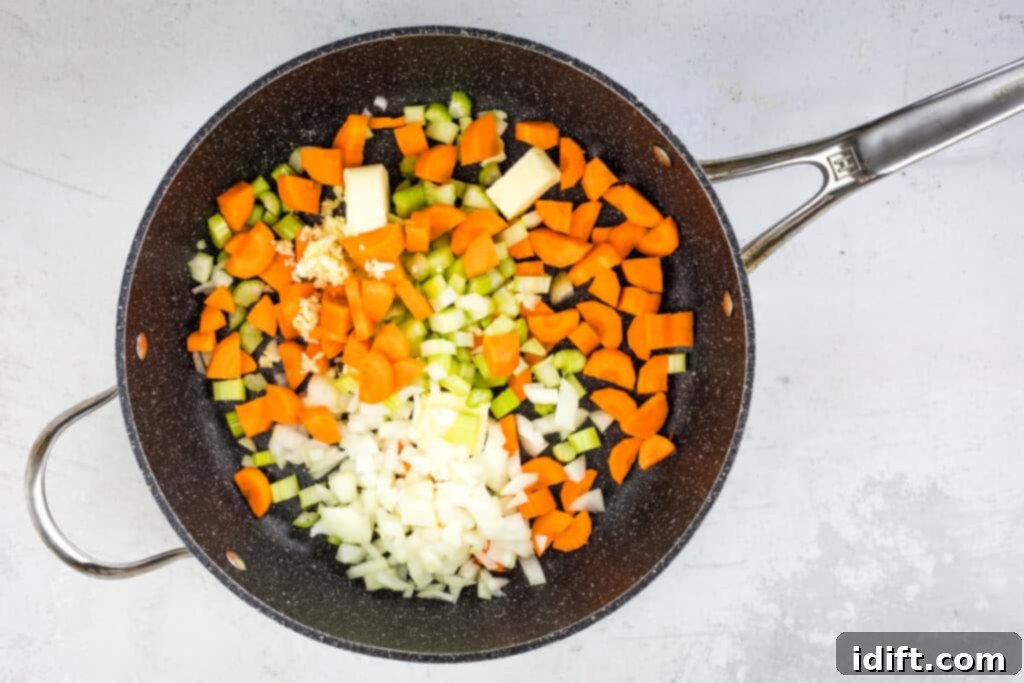 Diced carrots, celery, and onion gently sautéing in melted butter in a skillet.