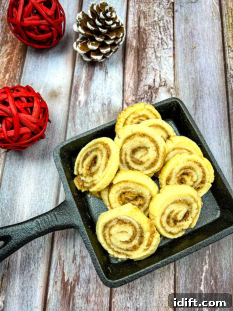 Golden-brown cinnamon roll cookies arranged on a rustic black cast iron dish, exuding a comforting warmth.
