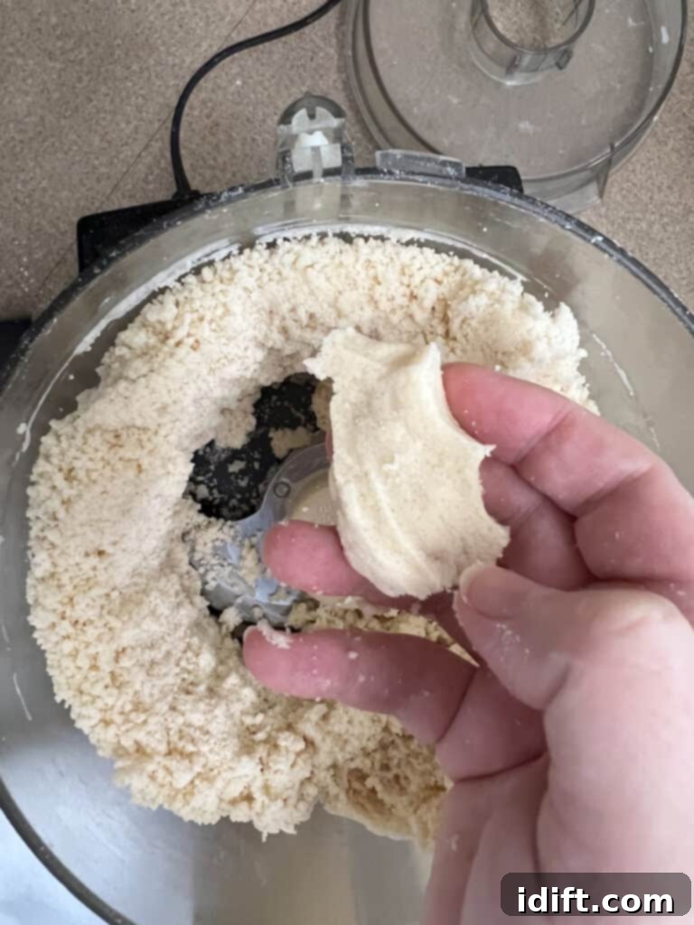 a hand holding a ball of cinnamon roll cookie dough