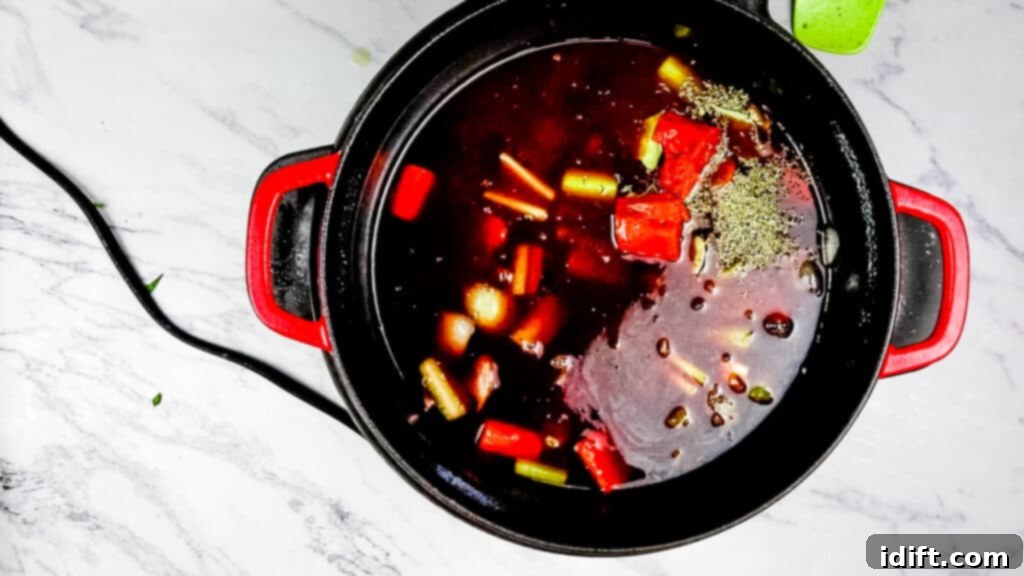 Pouring red wine and beef broth into the Dutch oven with tomato paste, herbs, and spices.