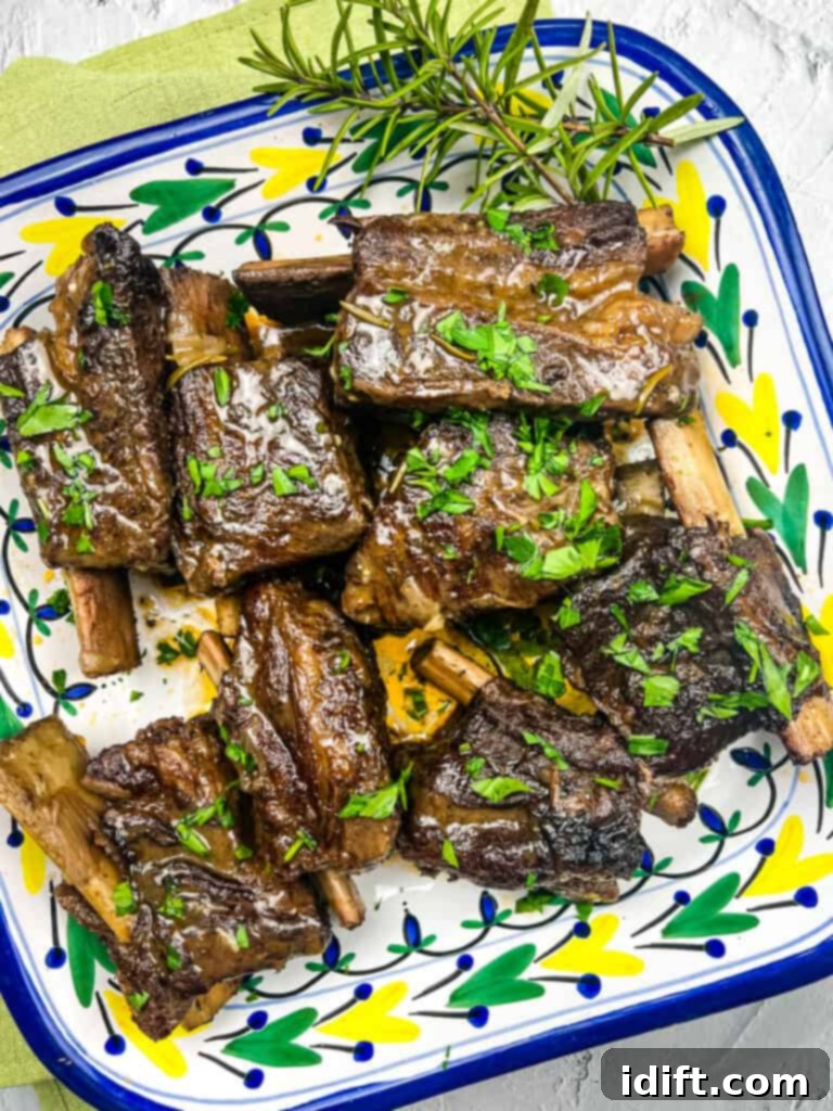 Tender garlic braised short ribs artfully arranged on a large platter, garnished and ready to serve.