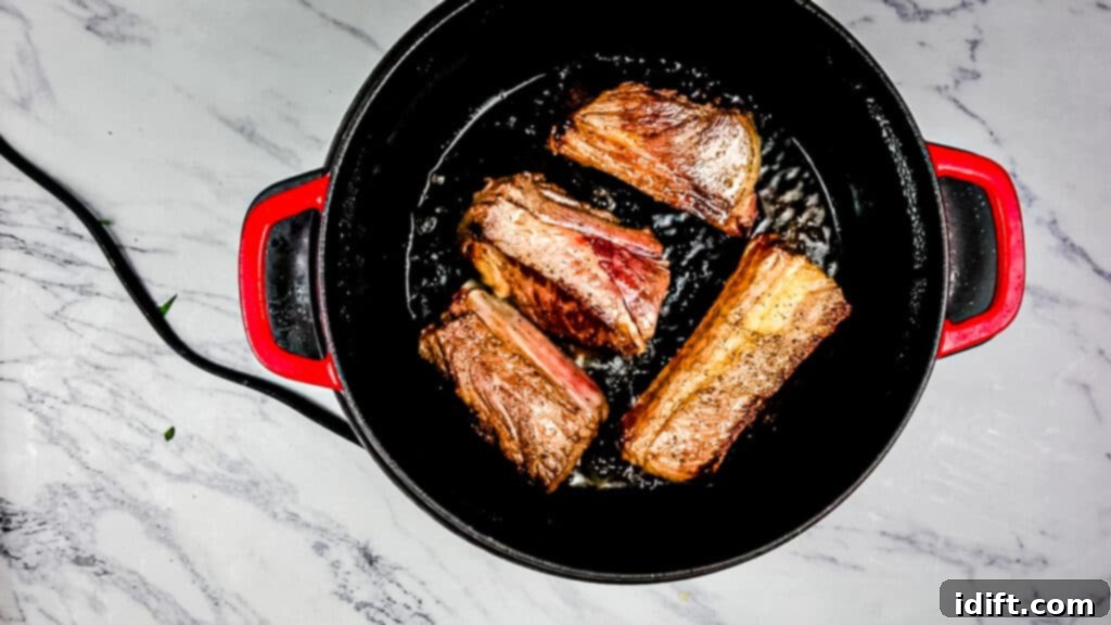 Bone-in beef short ribs searing to a deep golden brown in the Instant Precision Dutch Oven, developing rich flavor.