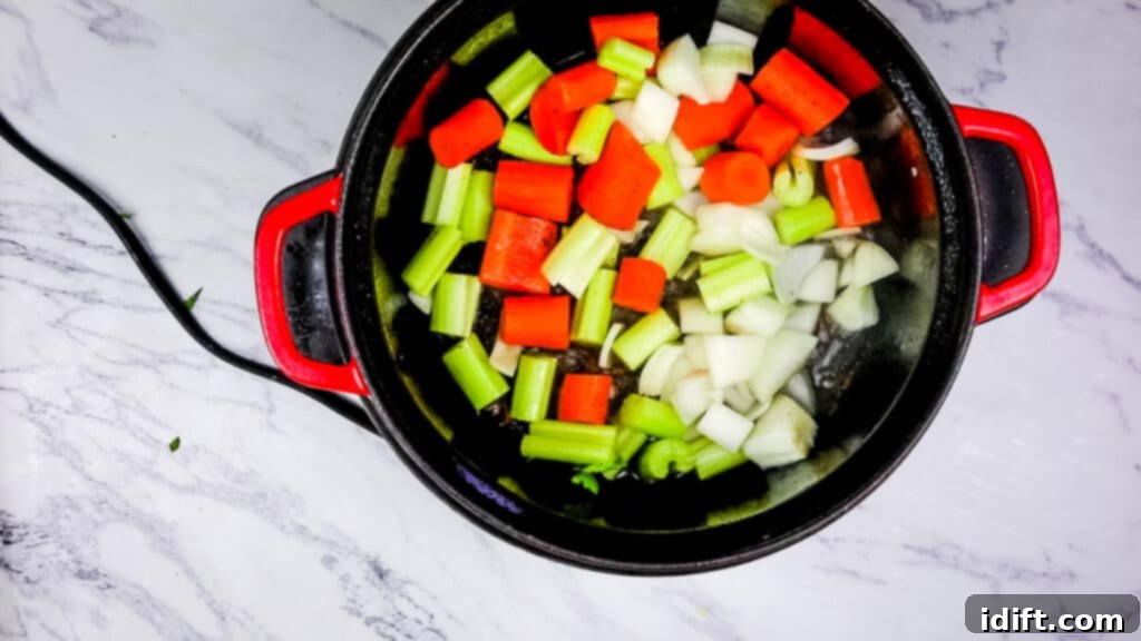 Chopped carrots, onions, celery, and garlic sautéing in the Dutch oven, creating an aromatic base.