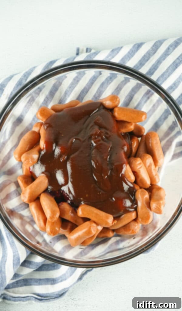 mixing smokies with sauces in a bowl to make smoked little smokies