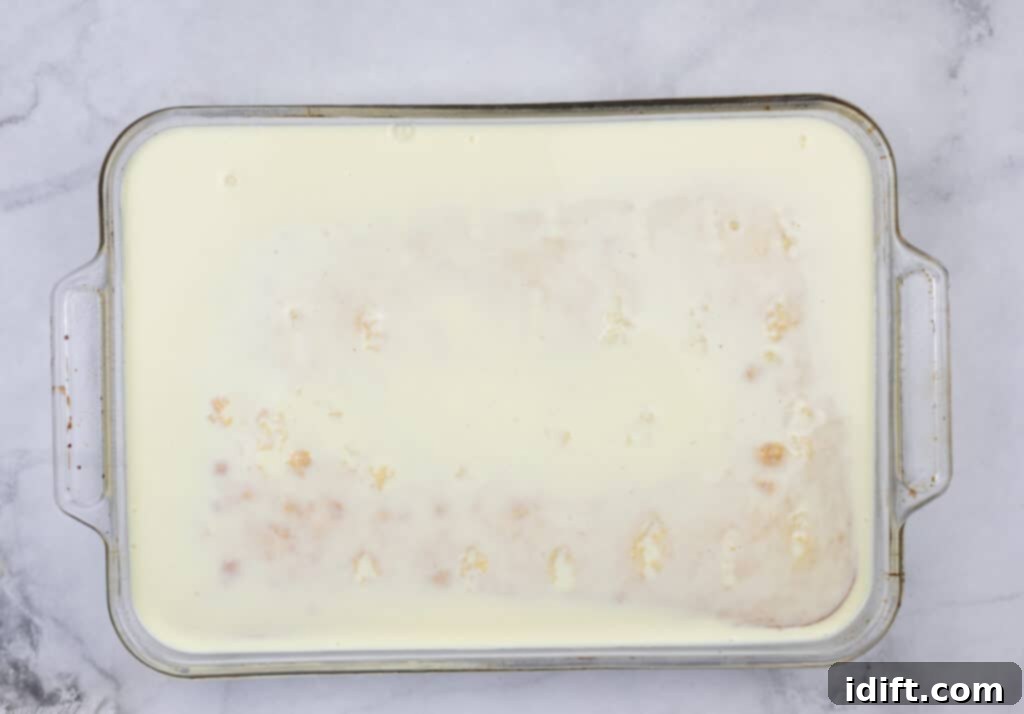 The cooked cake being covered with the eggnog and milk mixture, allowing it to soak.