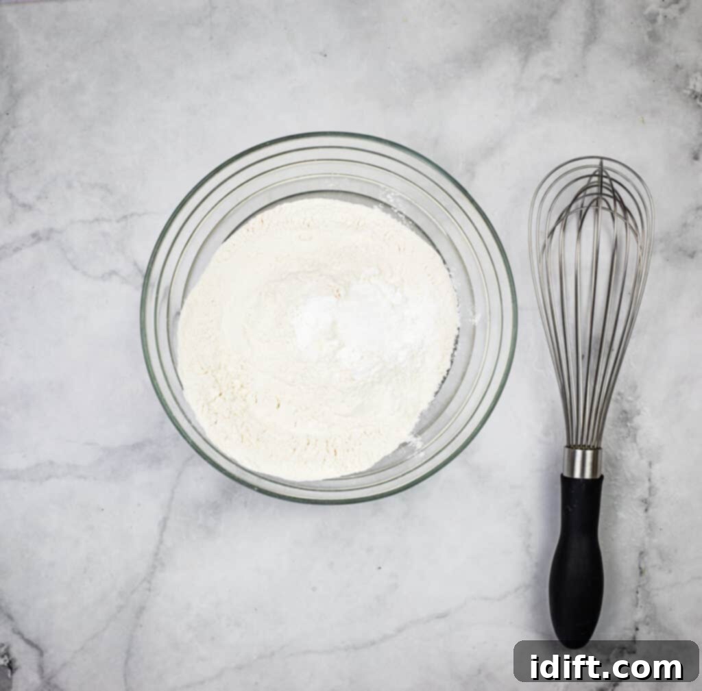 A bowl containing flour, salt, and baking powder, ready to be blended.