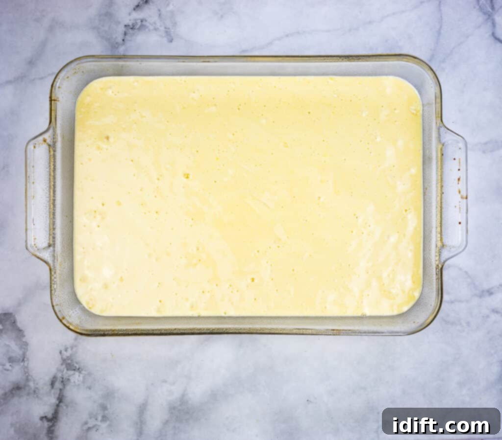 Eggnog Tres Leches cake batter poured into a 9 x 13 baking dish, ready for the oven.