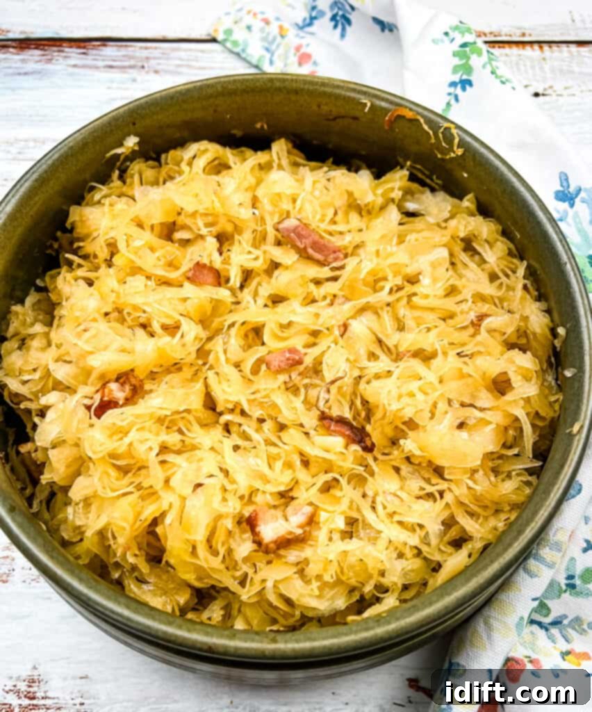 A casserole dish filled with baked sauerkraut, apples, and bacon, ready to be served.