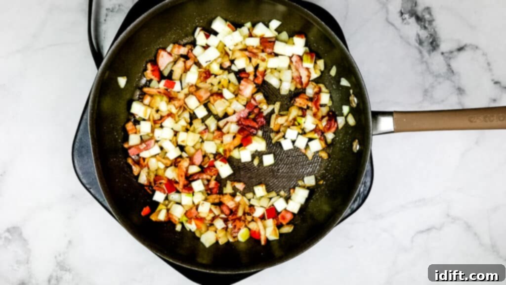 Sautéing the onion, bacon, and diced apple in a skillet, combining the flavors.