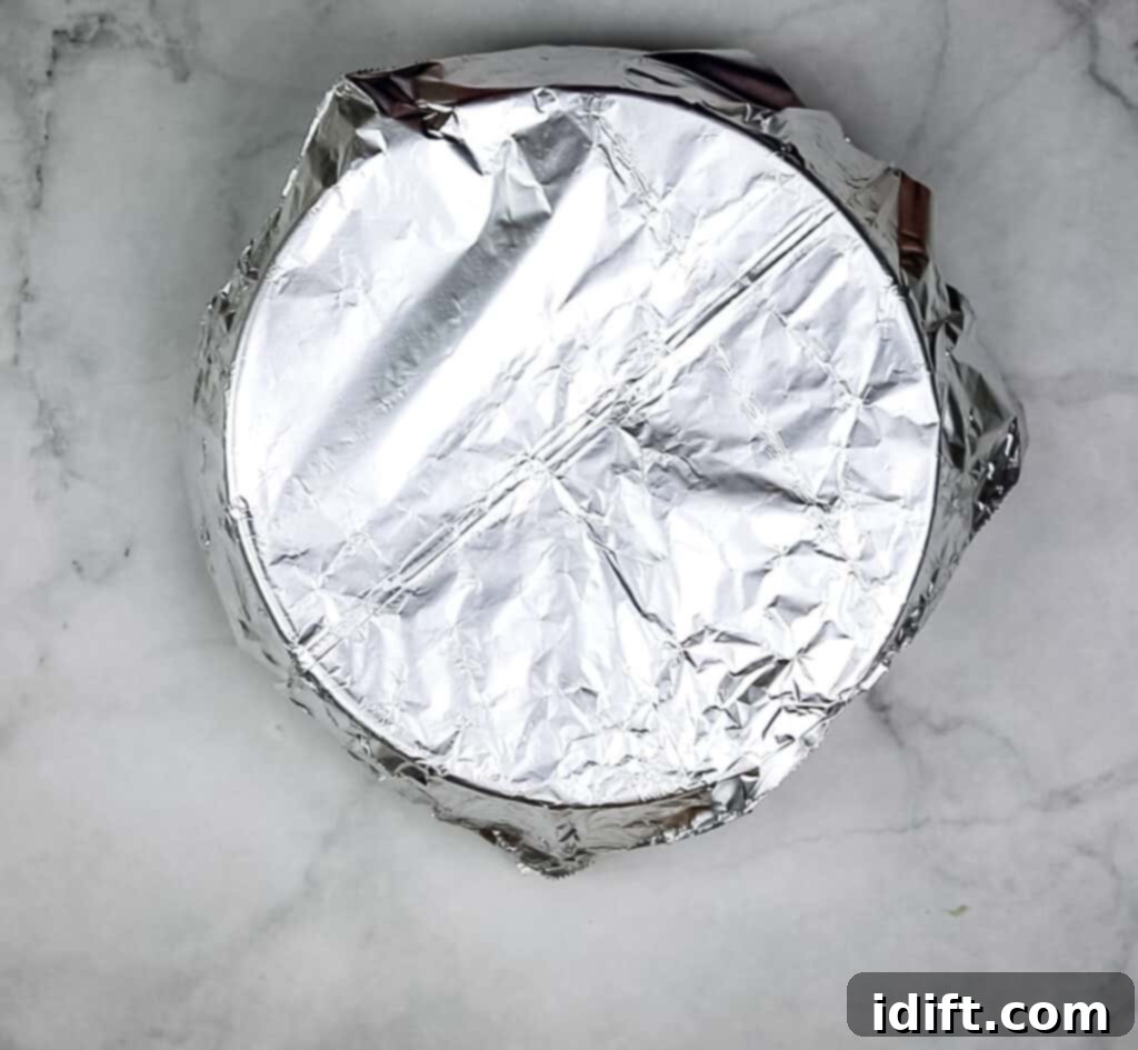 A casserole dish covered with foil, containing the sauerkraut, bacon, and apple mixture, ready for baking in the oven.