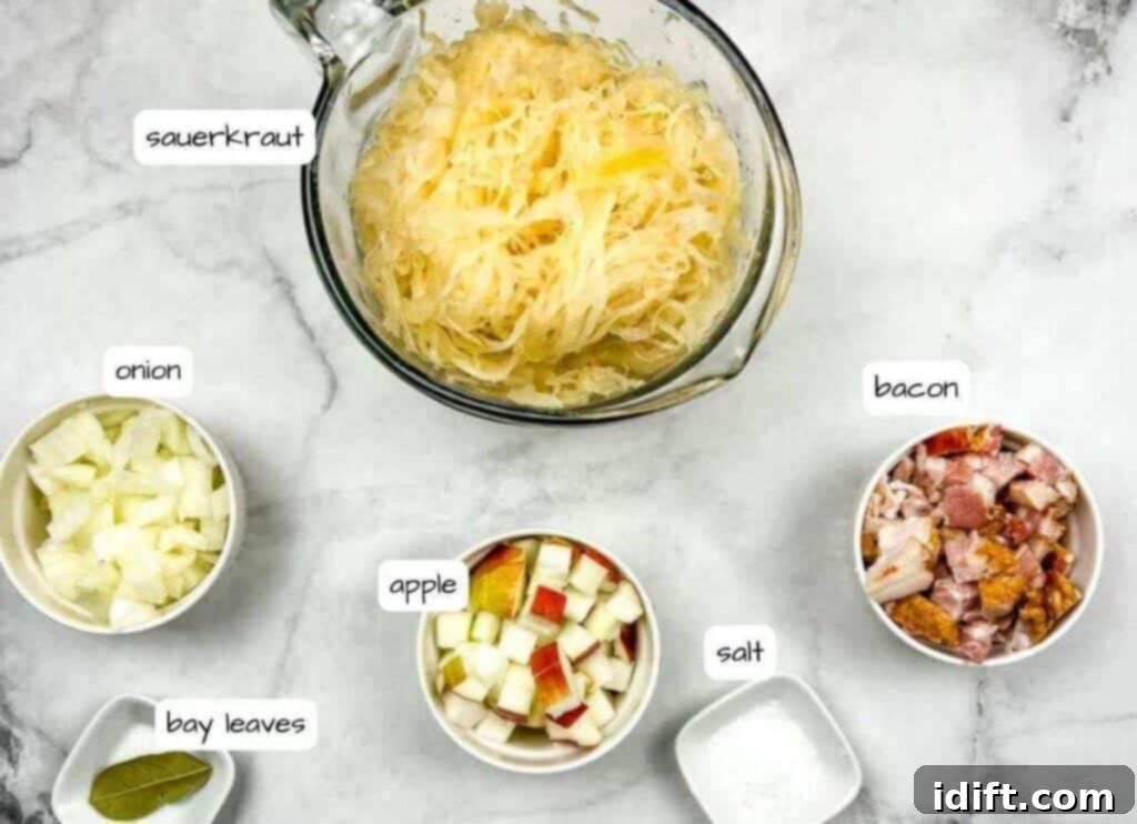 Labeled ingredients laid out for making baked Sauerkraut with Apples & Bacon: sauerkraut, onion, apple, bacon, bay leaf, salt, and pepper.