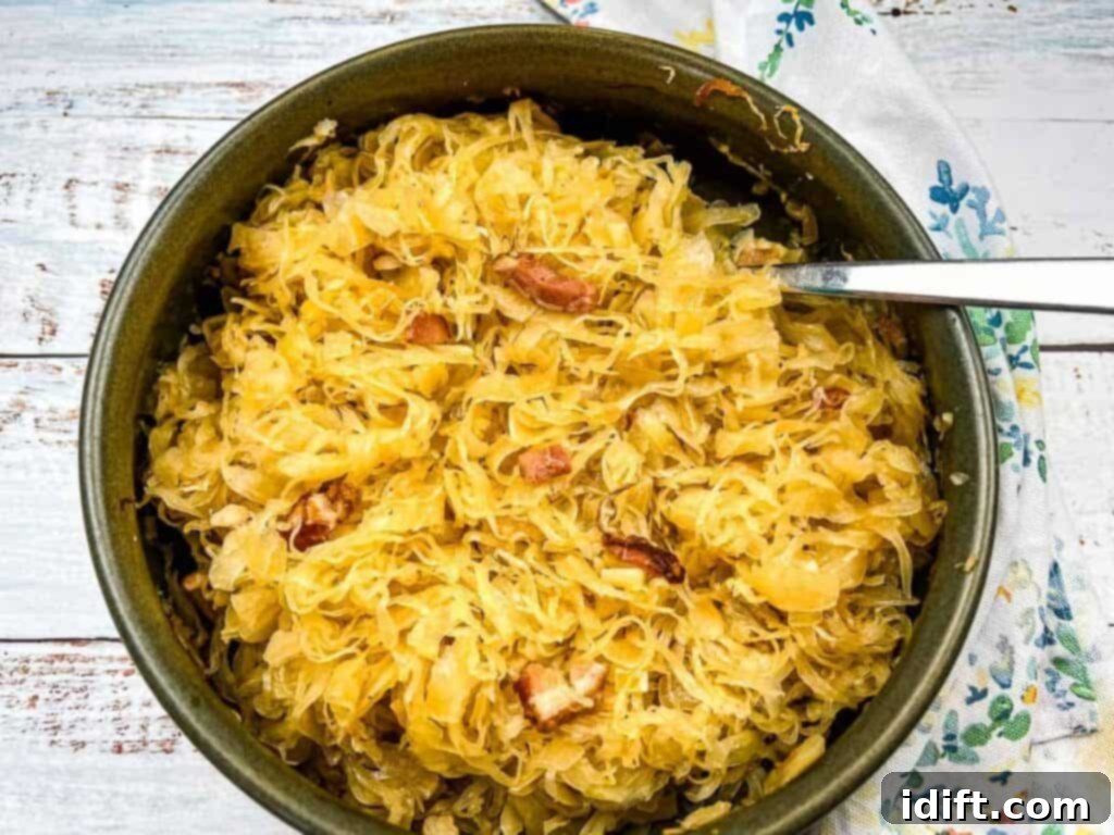 A serving dish filled with baked sauerkraut with apples and bacon, with a spoon nestled in it, ready to be enjoyed.