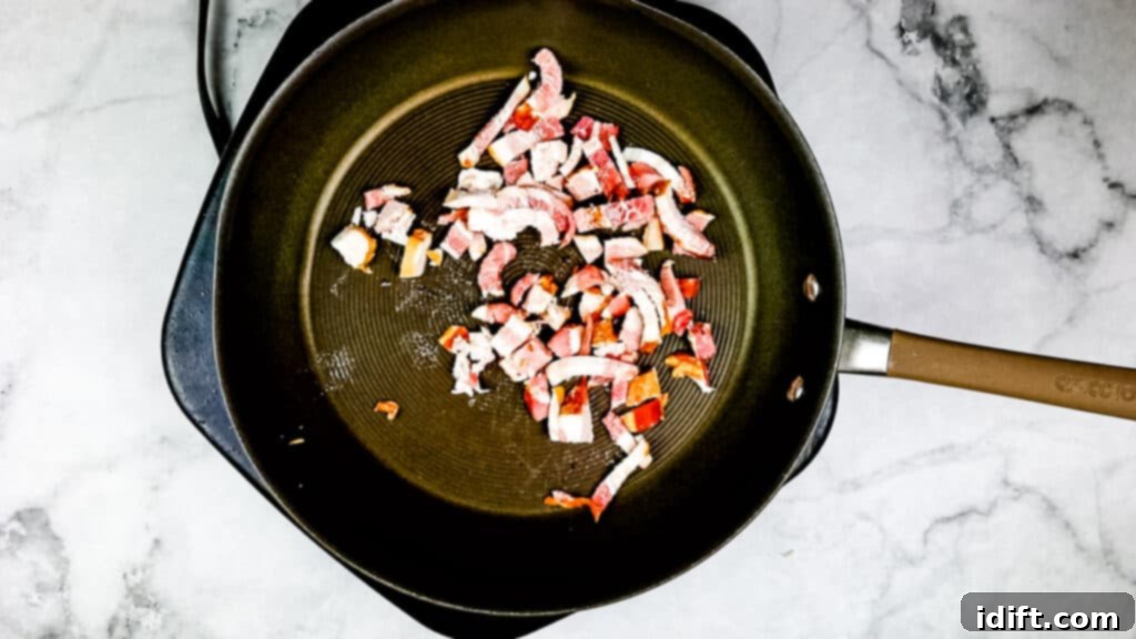 Cooking chopped bacon in a skillet until crispy to prepare sauerkraut with apples and bacon.