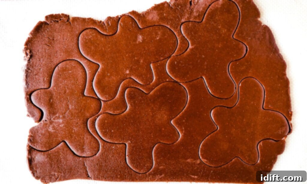 Rolled out chocolate gingerbread dough with cookie shapes cut out and ready for baking.