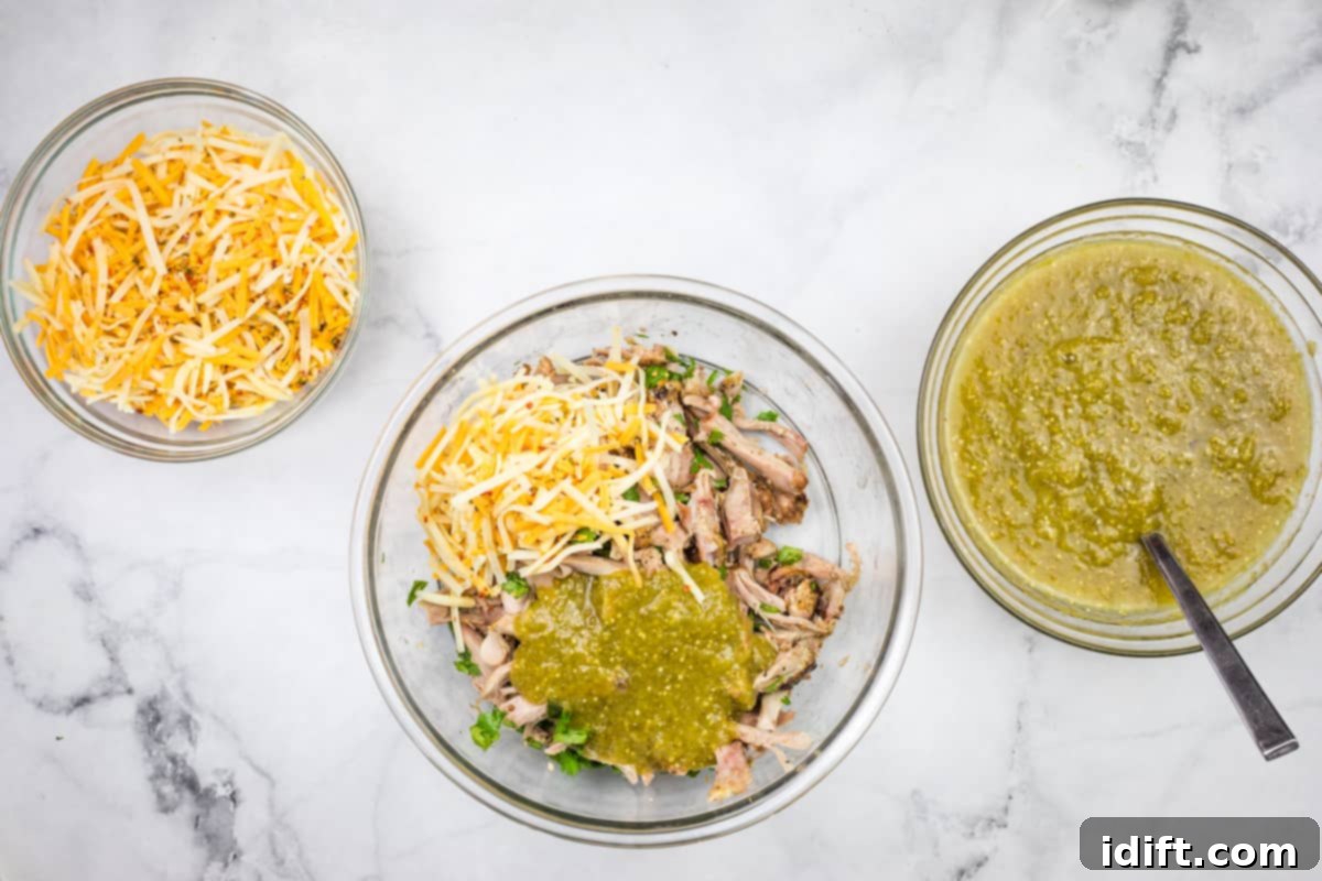 A bowl of chopped chicken, sauce and cheese.