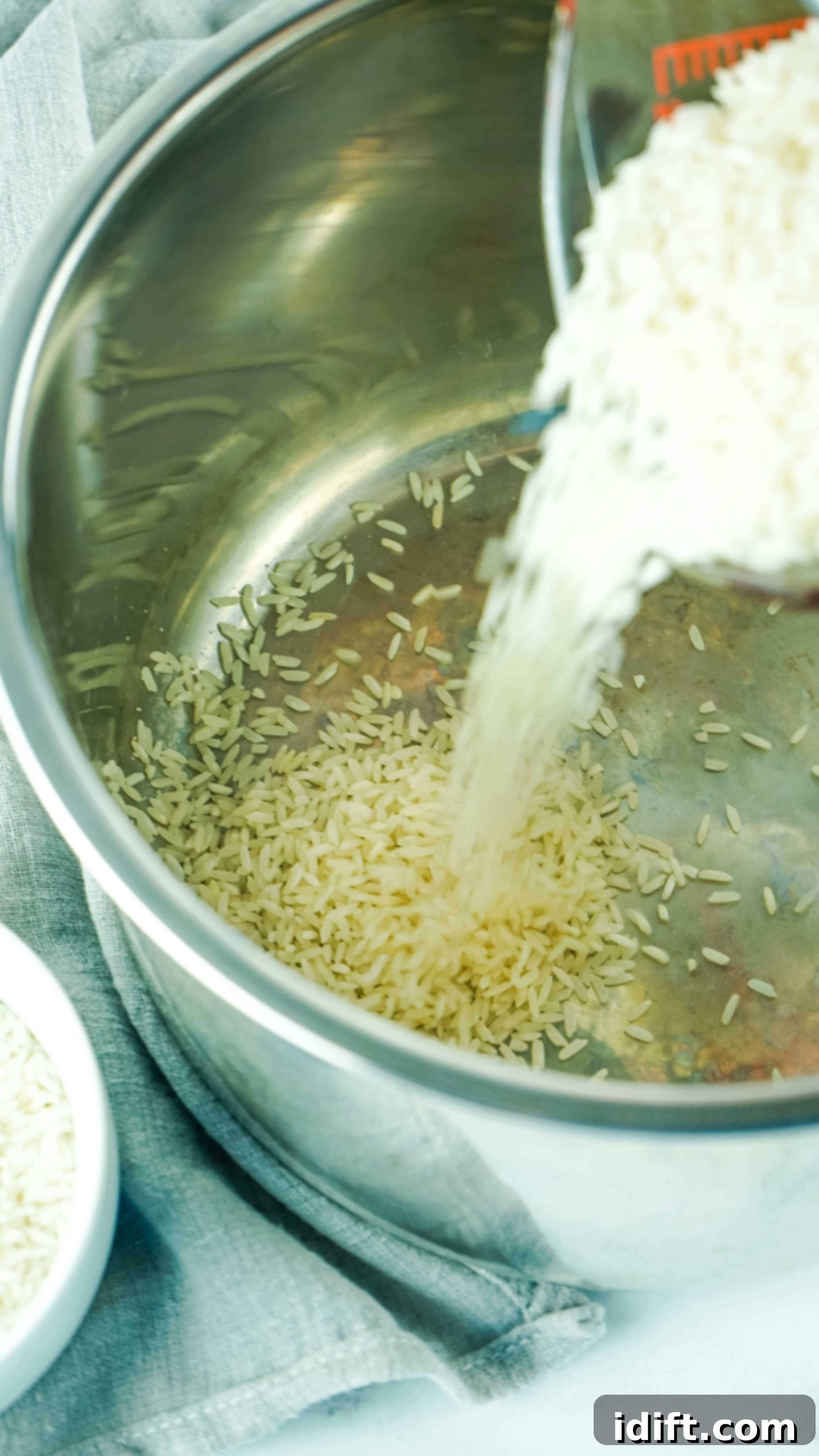 Foolproof Instant Pot Rice 5 A hand adding white rice to the Instant Pot's inner stainless steel insert.