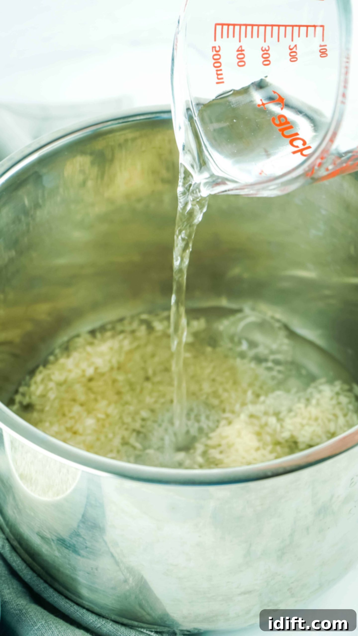 Foolproof Instant Pot Rice 6 A hand pouring water into the Instant Pot insert with rice already inside.
