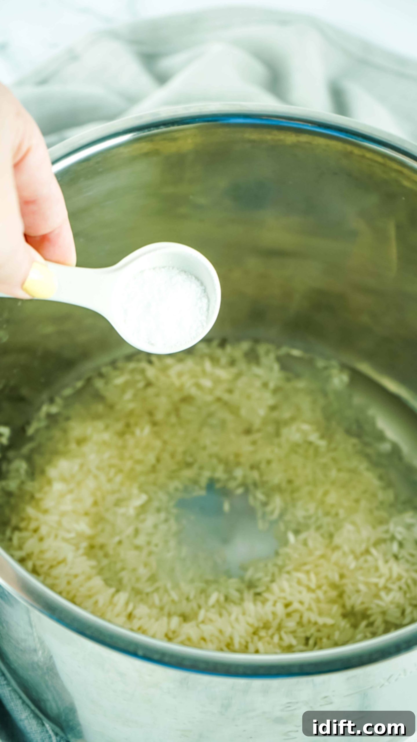 Foolproof Instant Pot Rice 7 A hand adding a pinch of salt to the Instant Pot insert containing rice and water.