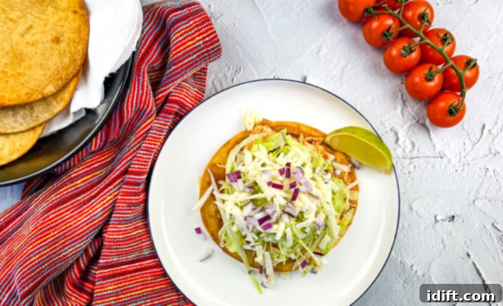 A beautifully assembled chicken tinga tostada topped with fresh ingredients, ready to be enjoyed.
