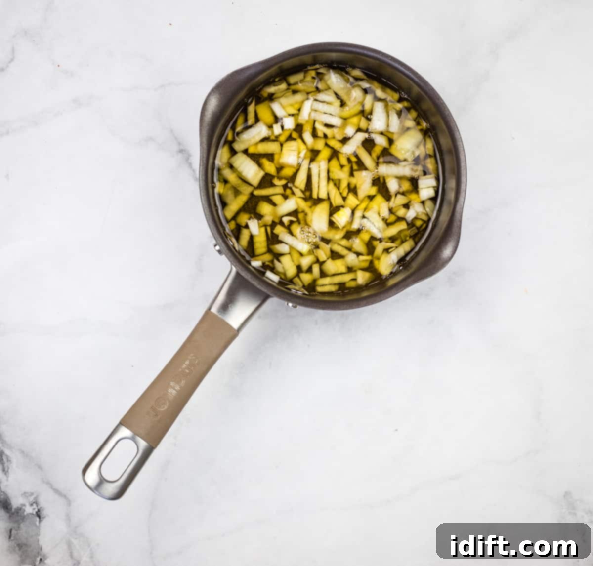 Chipotle Bourbon BBQ Sauce 4 Onions simmering in bourbon in a small pot on the stove, steam rising, indicating the reduction process is underway for the BBQ sauce base.