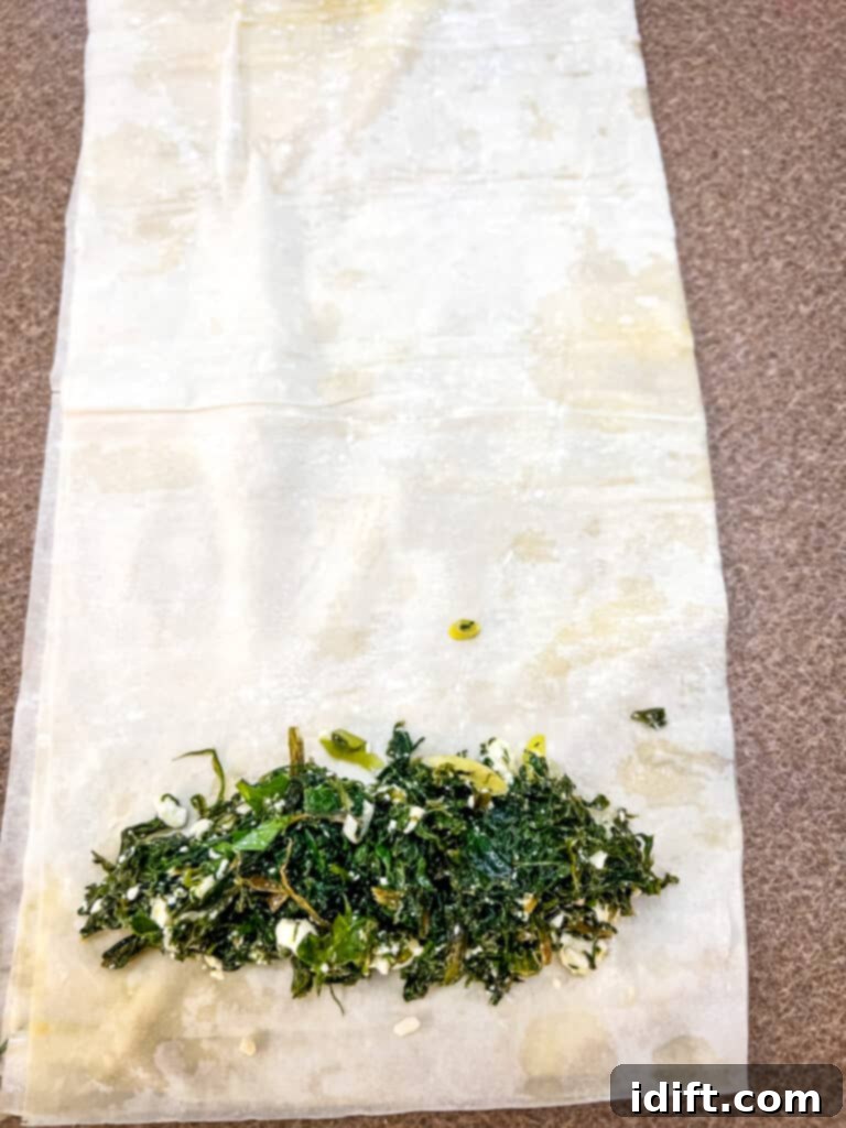 filling and rolling the phyllo sheets to make spanakopita rolls