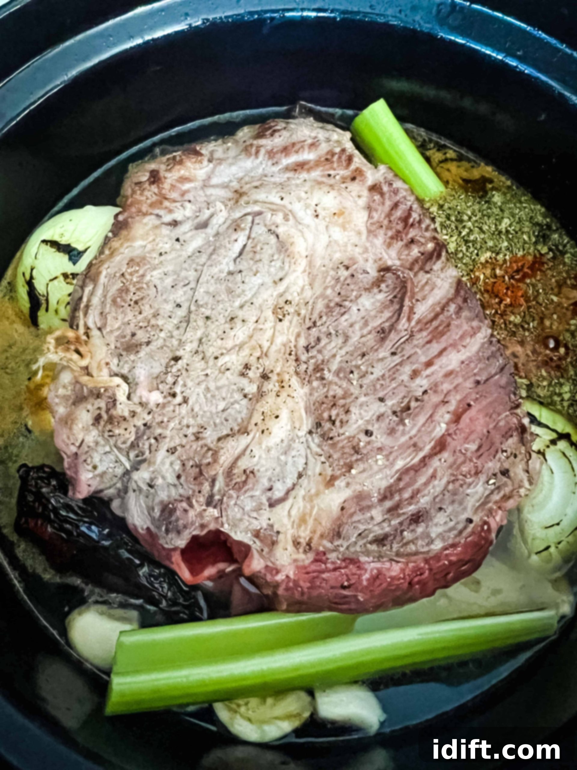 beef, vegetables, chilis and broth in the dutch oven ready for braising.
