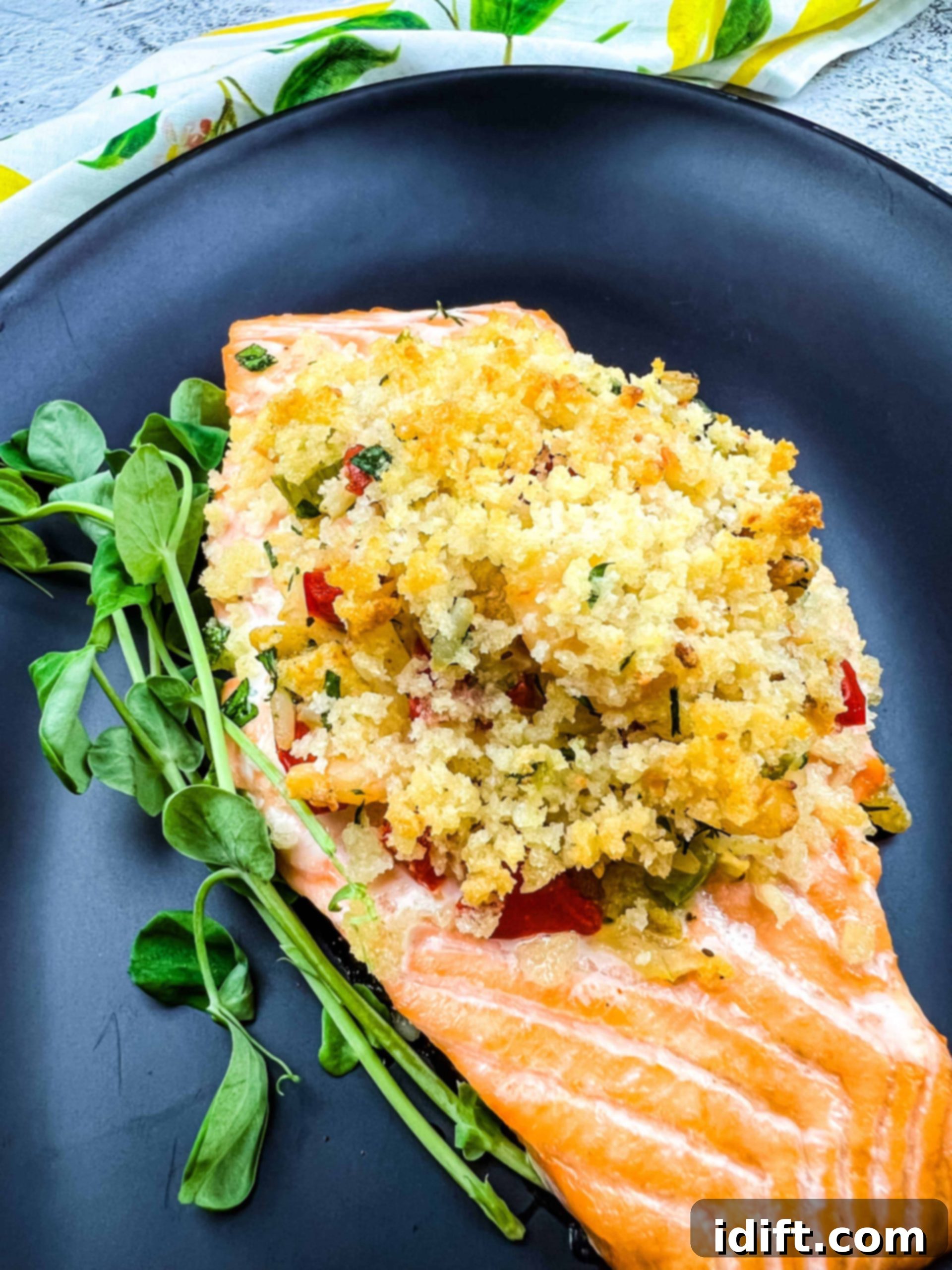 seafood stuffed salmon filet on a black plate, garnished with fresh herbs