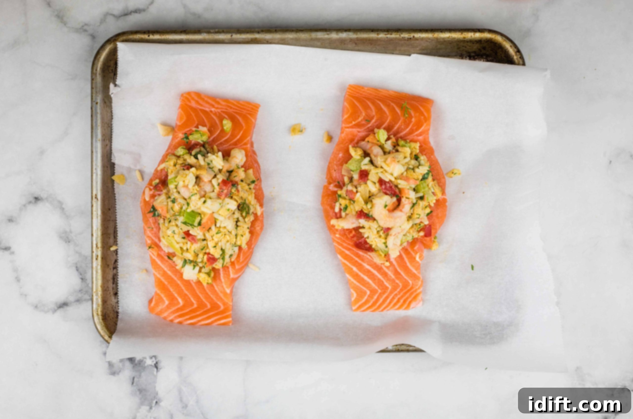 Salmon fillets on a baking sheet, filled with seafood stuffing.