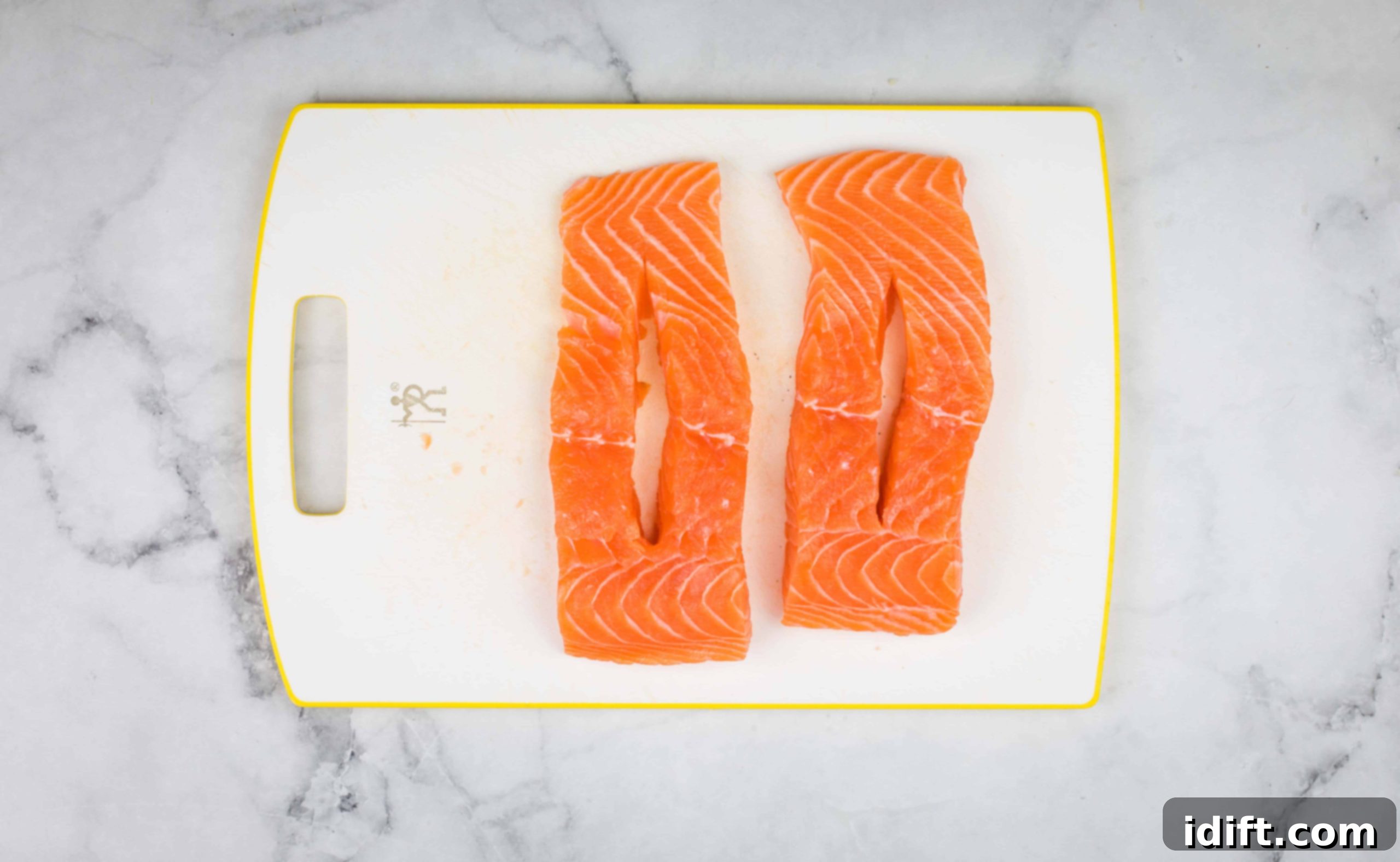 A salmon fillet on a cutting board with a lengthwise slit cut into it for stuffing.