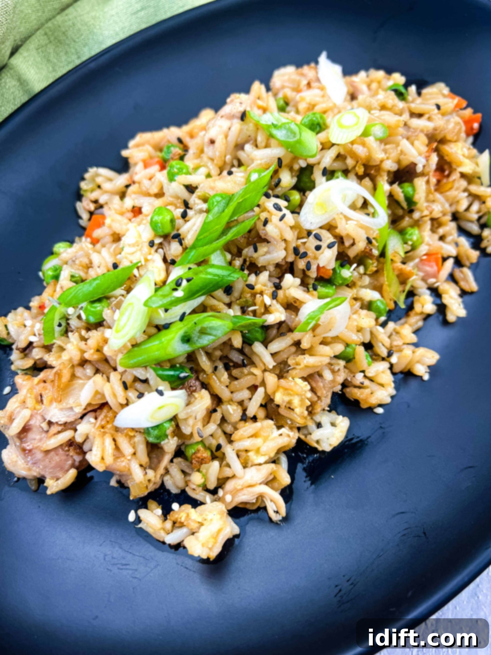 Crispy chicken fried rice with tender chicken chunks served on a black plate, fresh from the Blackstone Griddle.