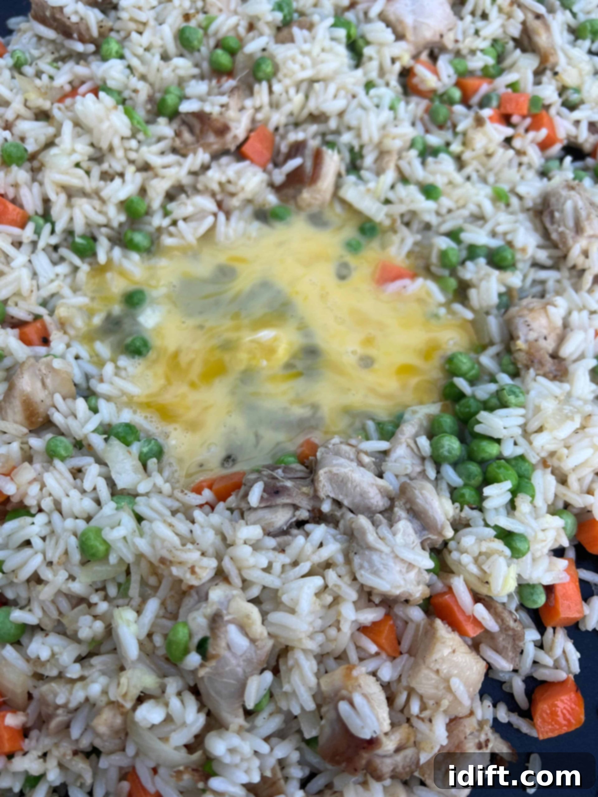Scrambling an egg in a cleared section of the griddle before mixing it into the fried rice.